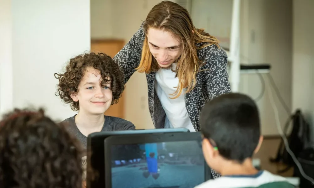 Un enfant et son formateur regarde un écran de code
