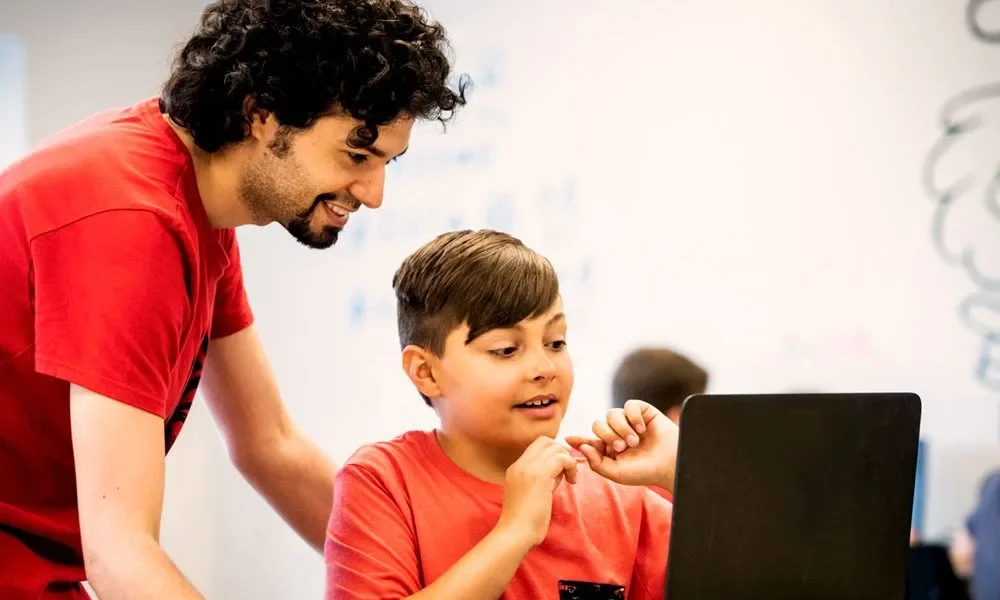 Un enfant et son professeur regarde un écran